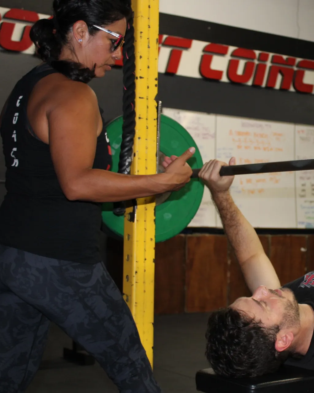 Coach Rosie spotting a member on the bench press, one on one